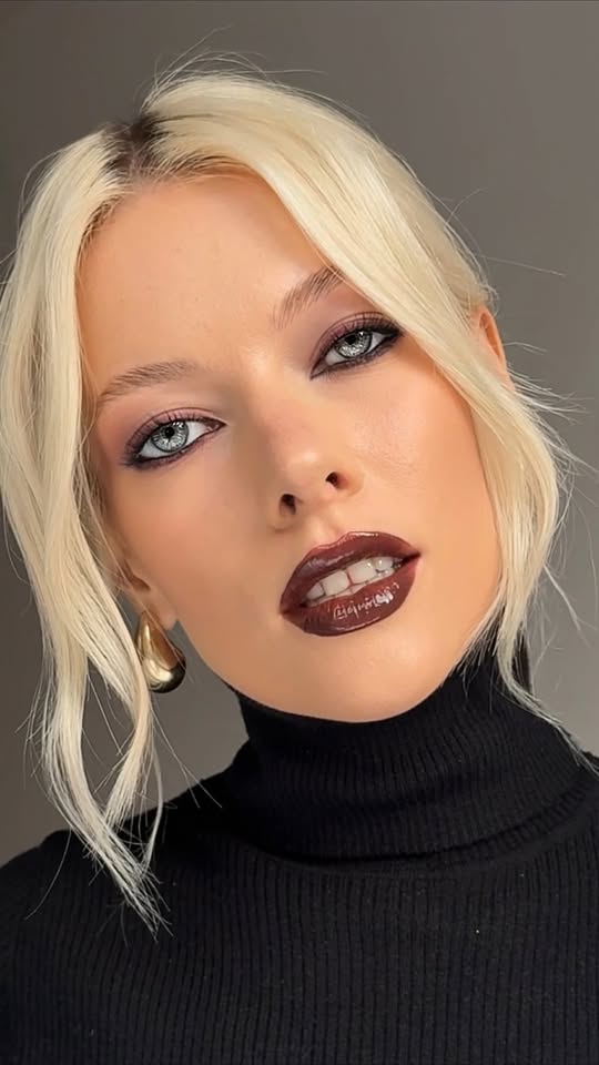Elena Rachitskaya applying pink lip gloss, with soft eye makeup and a pink tulle top.
