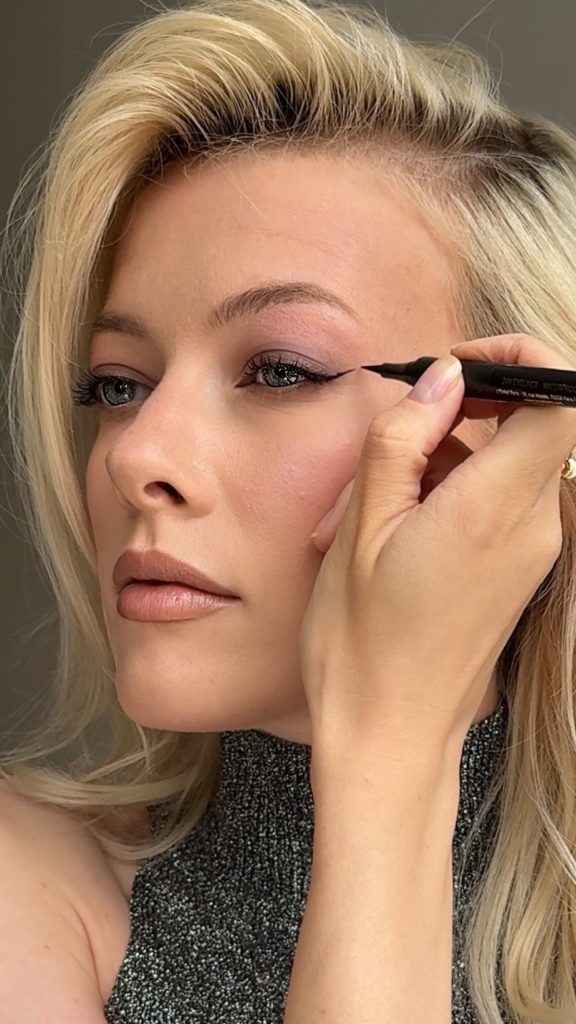 Elena Rachitskaya with deep wine-colored lips and defined eyeliner, against a black top in an editorial style.