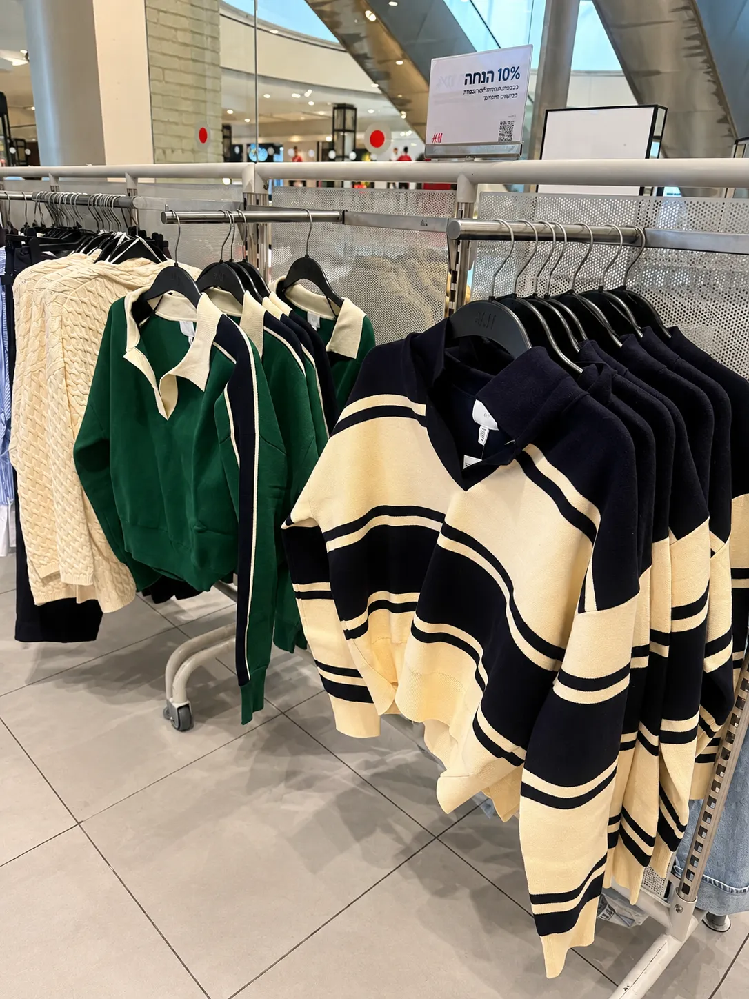 סריגי פסים וסריגים ירוקים על מתלה בחנות H&M