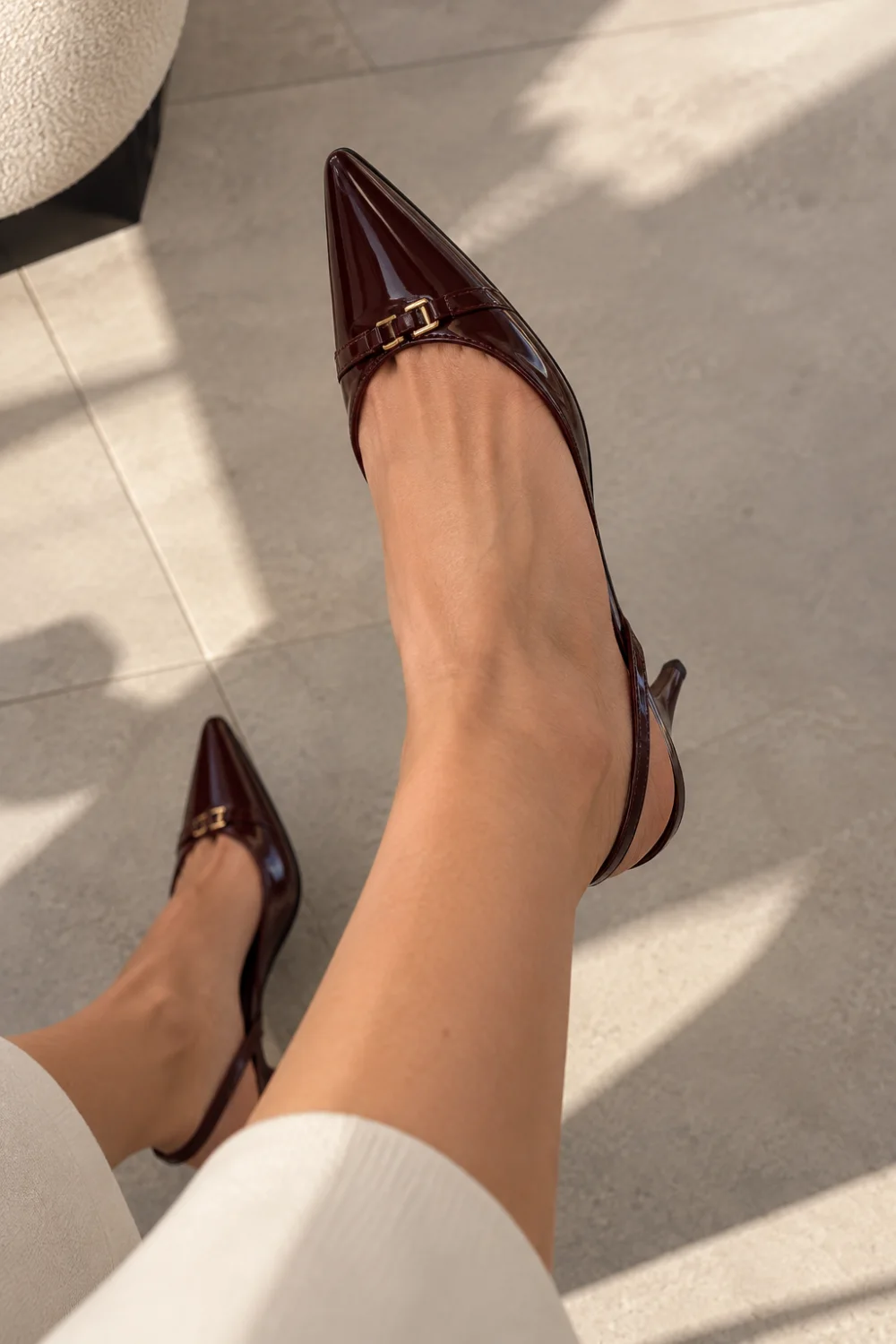 Burgundy patent slingback kitten heels worn with cream ribbed trousers