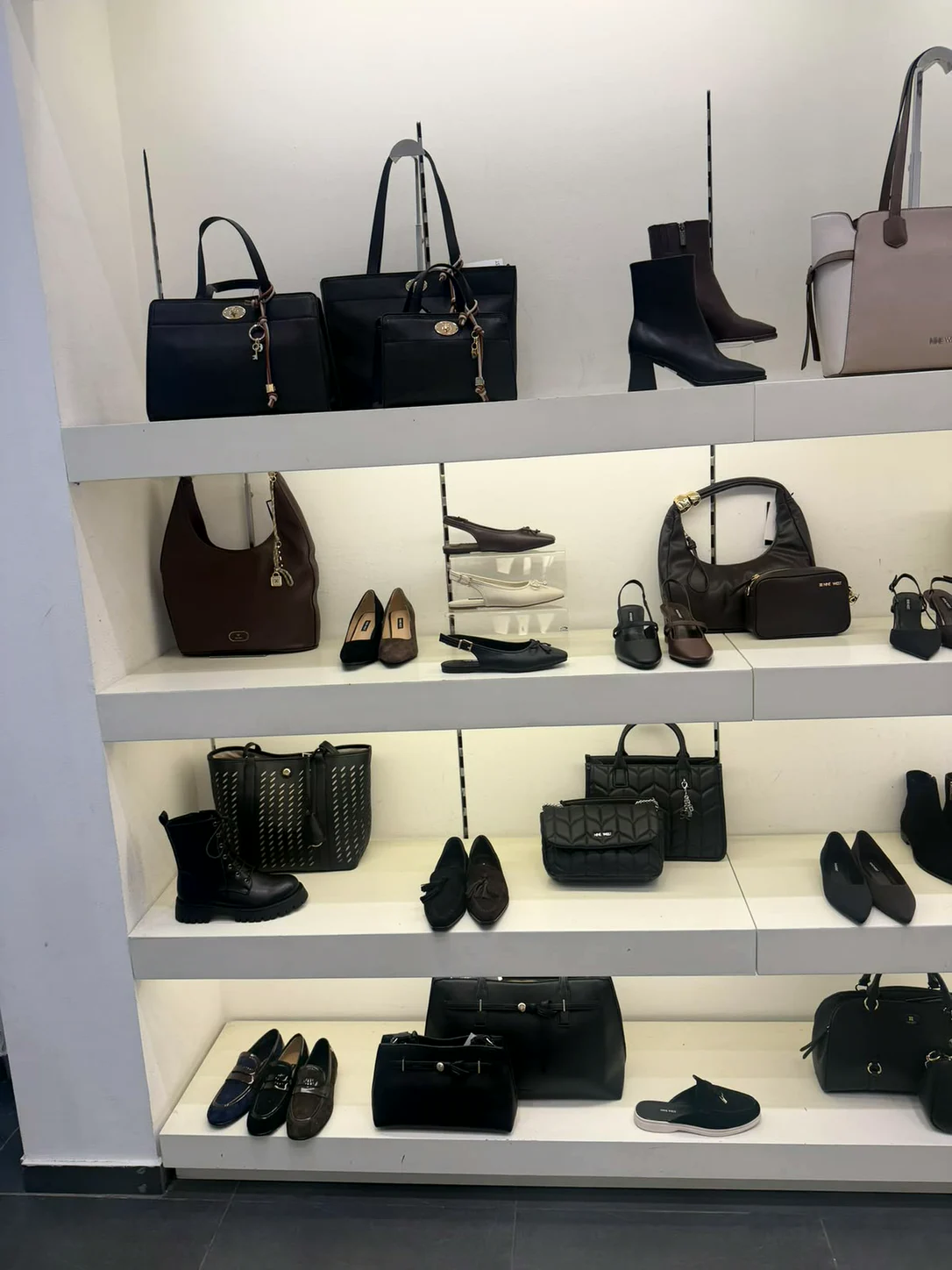 קיר תצוגה עם תיקים ומגפונים בחנות Nine West