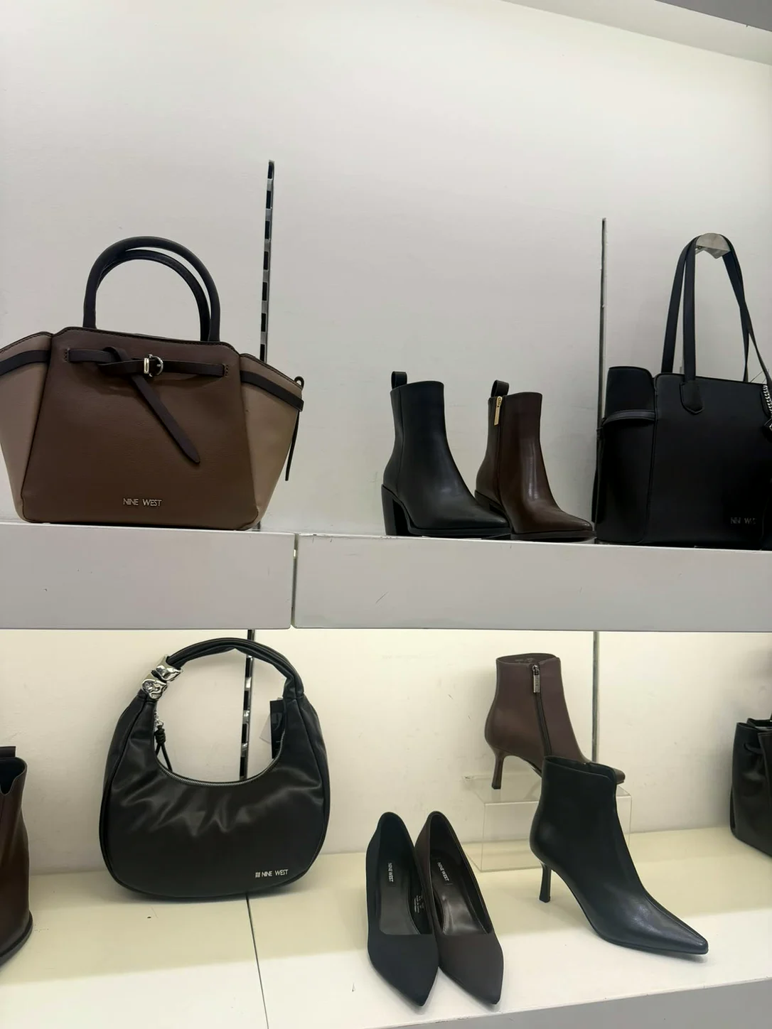 תיקים ומגפונים על מדפים לבנים בחנות Nine West