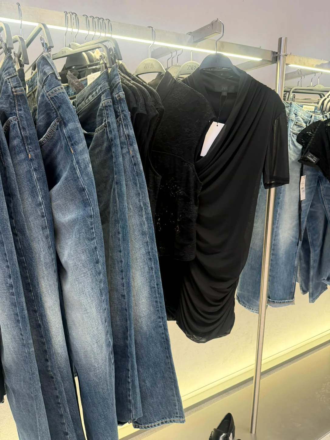 ג׳ינסים וטופ שחור עם כיווצים על מתלה בחנות Zara