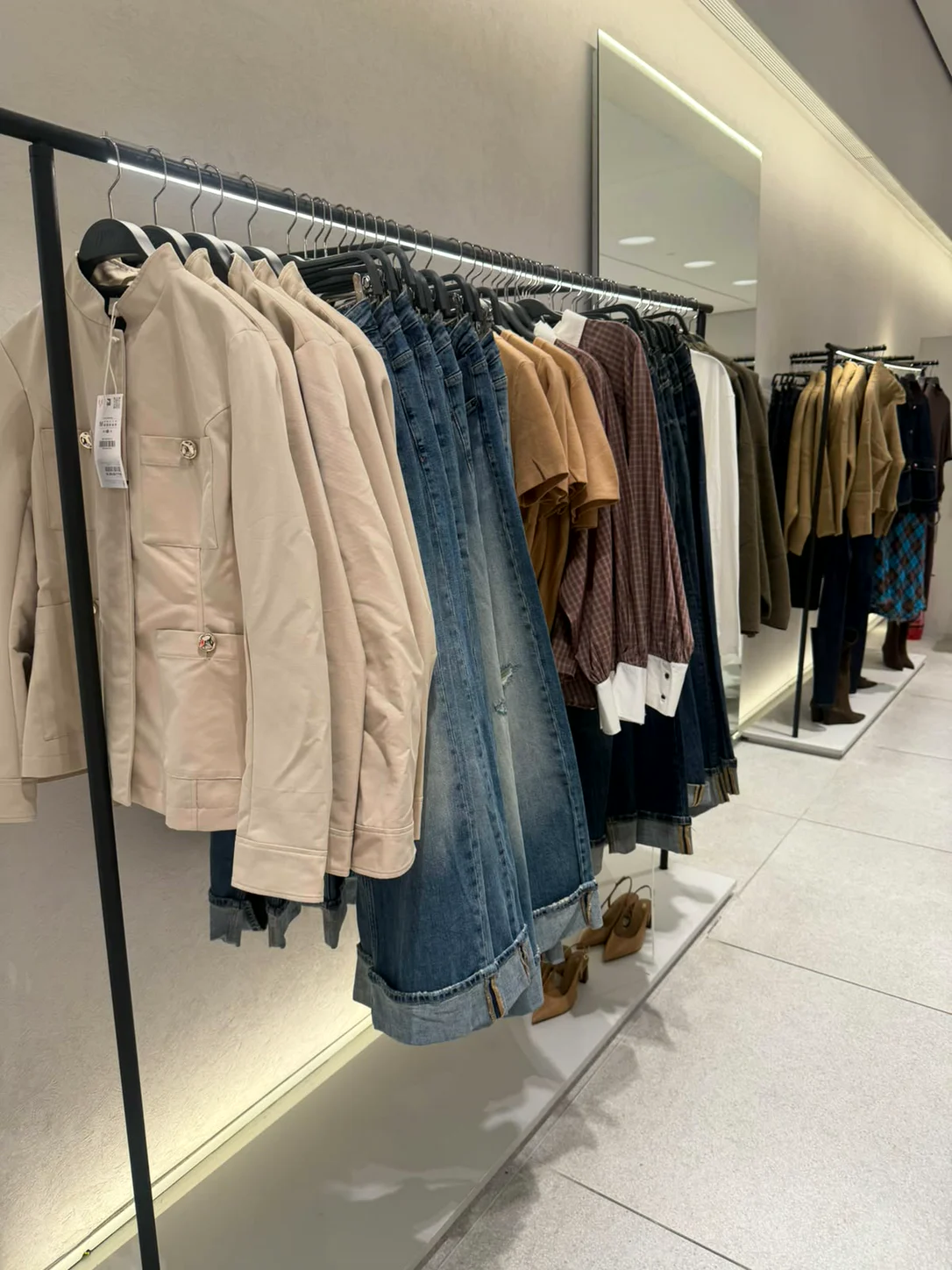 טרנצ׳ים בגווני קאמל וג׳ינסים על מתלה בחנות Zara